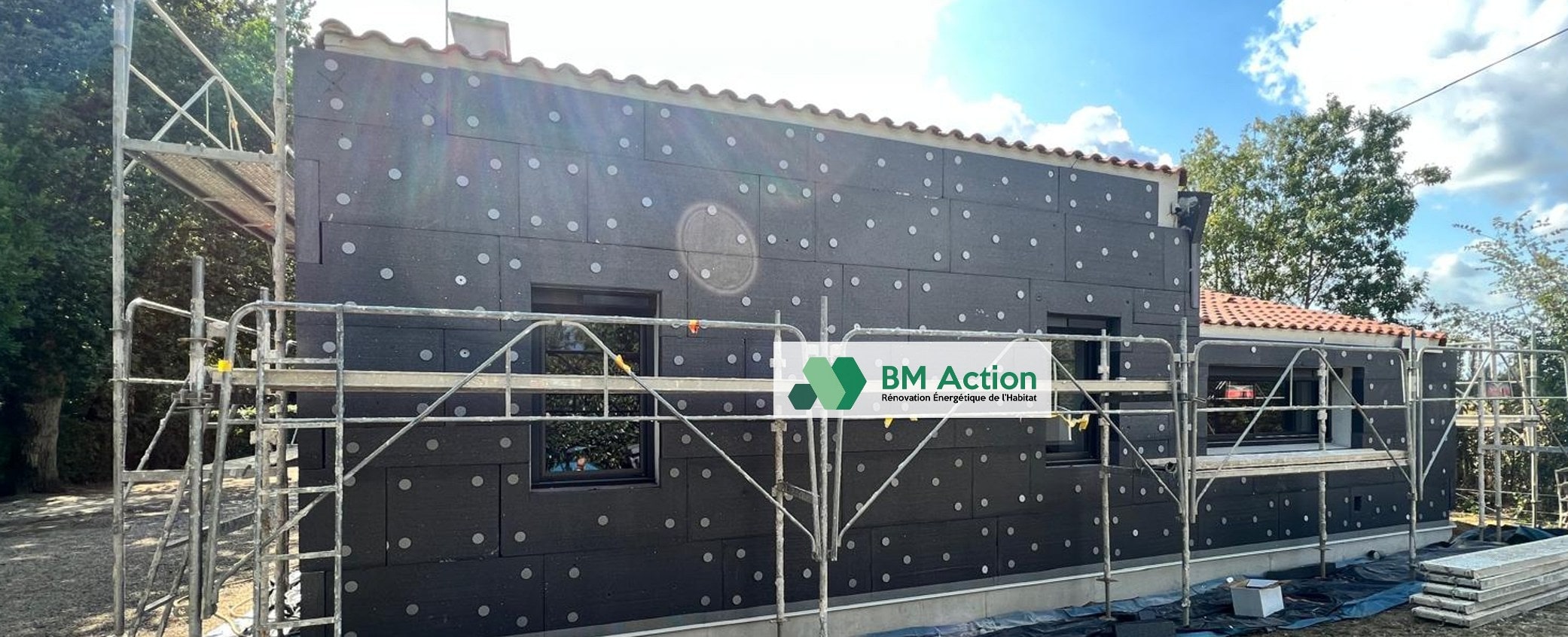Panneaux isolants posés sur une façade avec échafaudage et signalétique BM Action