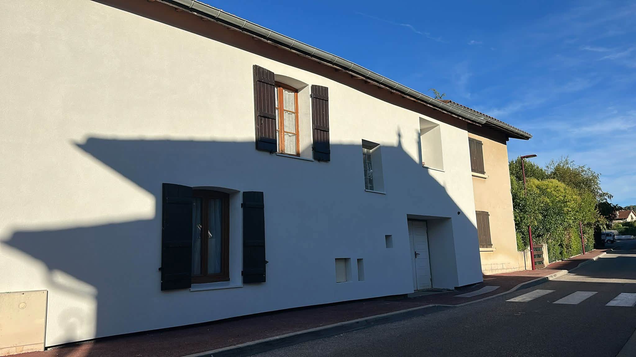 Réalisation BM Action : façade claire d’une maison à étage avec volets foncés