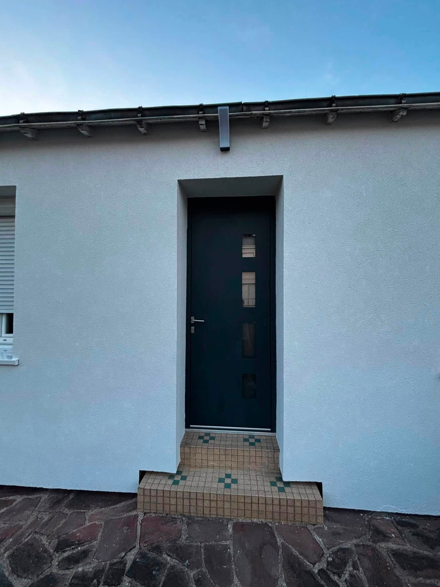 Façade enduite autour d’une porte anthracite — réalisation BM Action