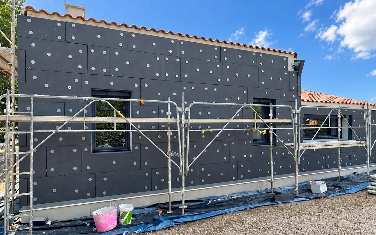 La façade pendant le chantier : panneaux isolants fixés et échafaudage en place