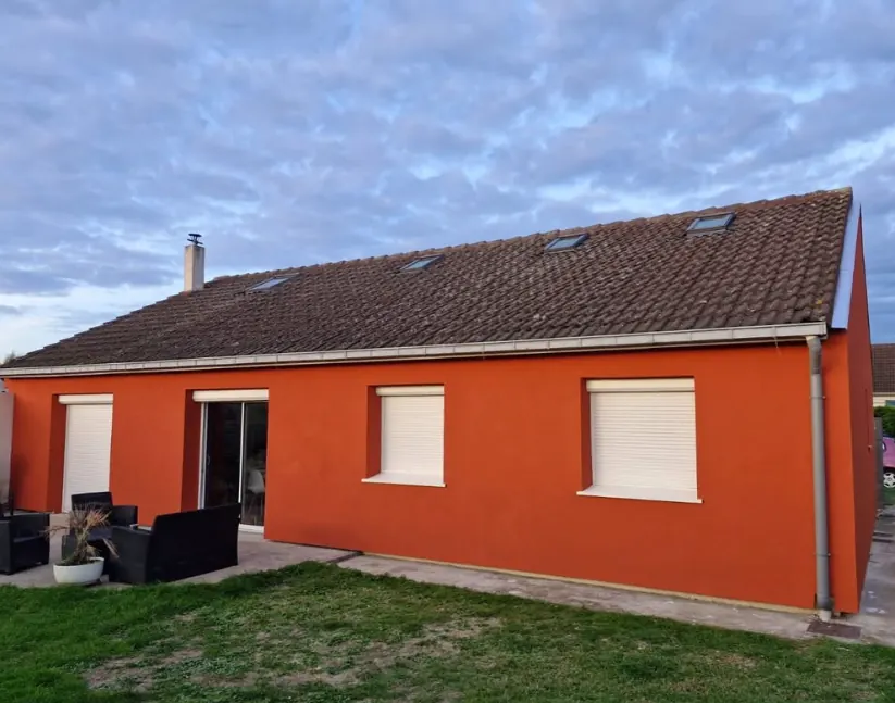 Maison enduite dans un ton terracotta, vue du jardin après isolation extérieure